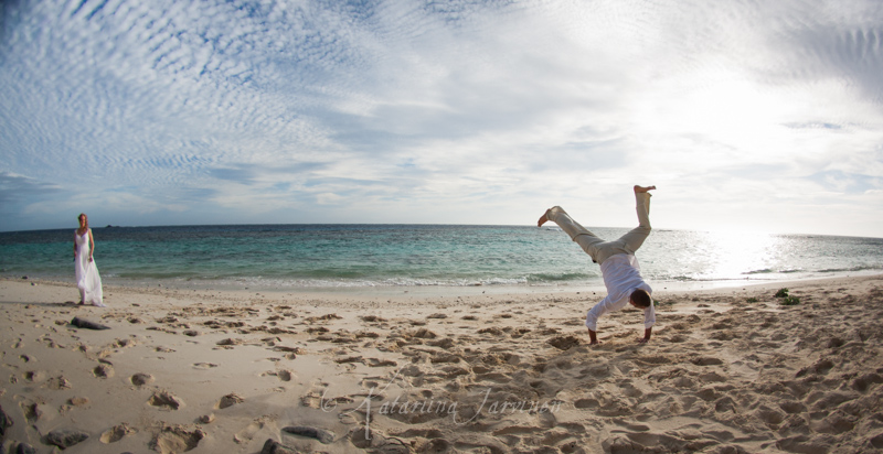 groom doing cartwheel on a sandy beach